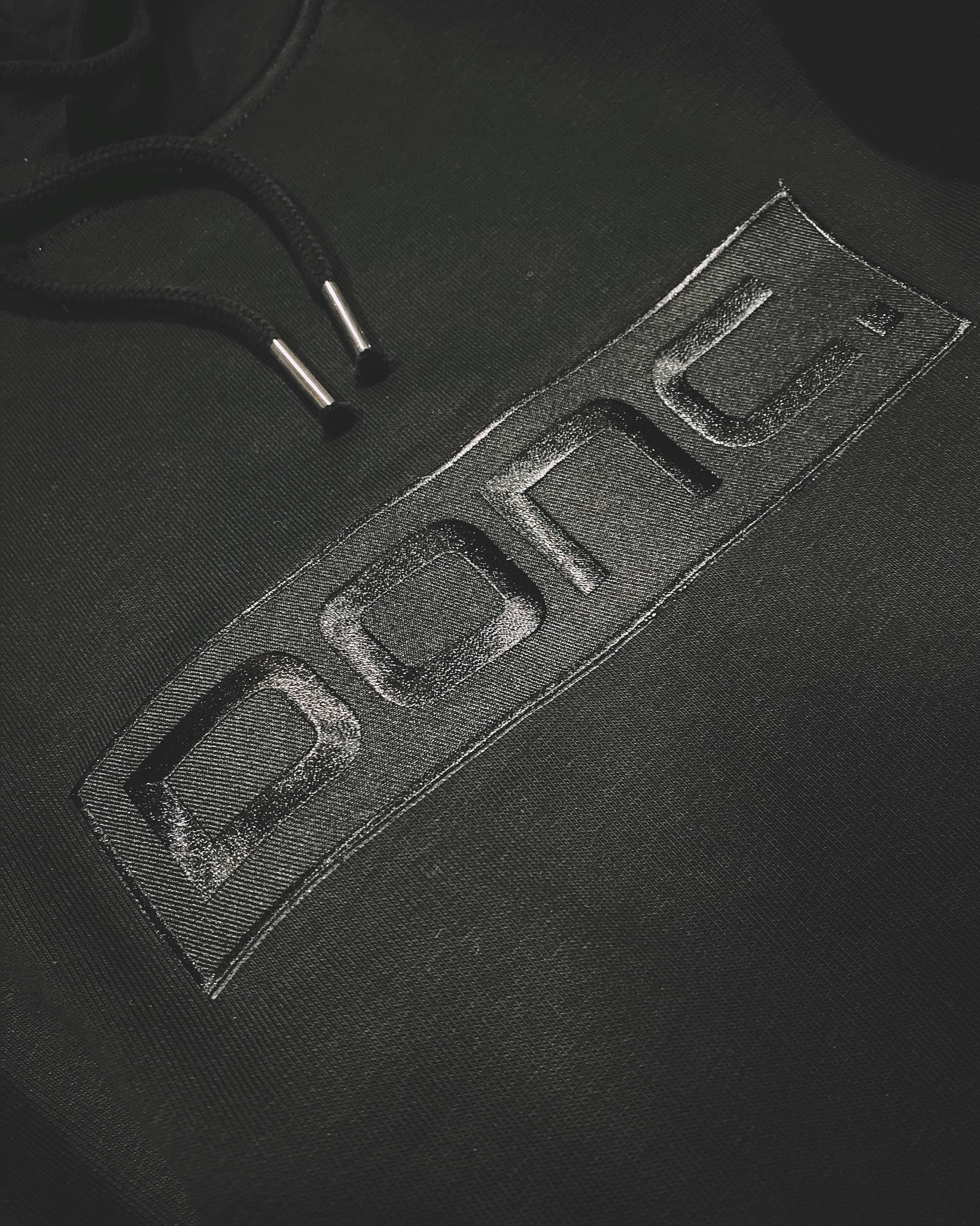 Rebranding DONC - detail nieuw logo op zwarte sweater